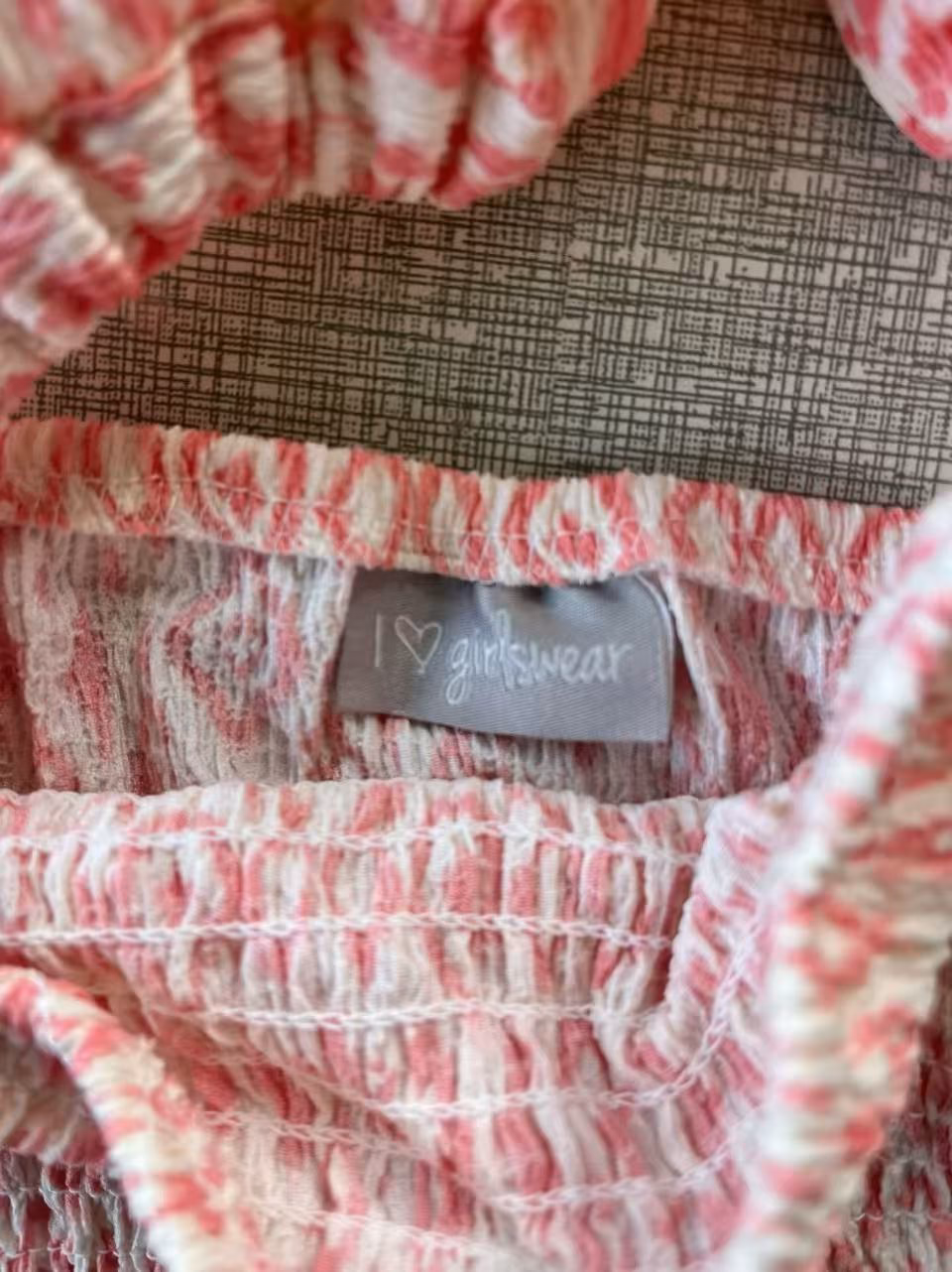 Brand tag and clothing label on the girls pink tie dye smocked top.