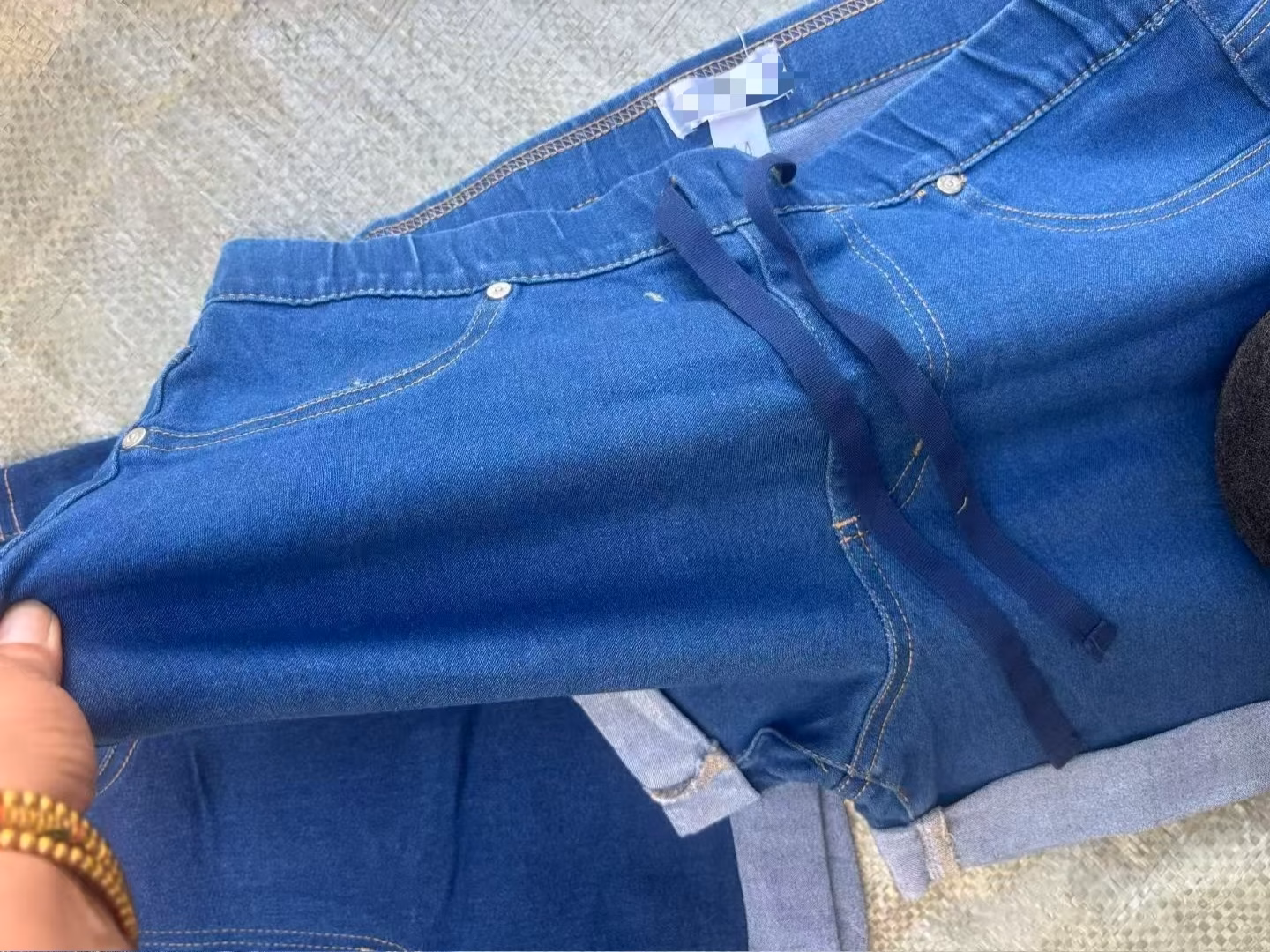 Close-up of flexible ribbed elastic denim waistband with contrast functional dark blue active drawstring